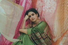 a woman sitting on the ground next to pink curtains