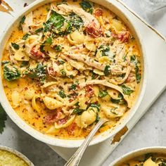 two bowls of pasta with chicken and spinach on the side, one bowl is filled with soup