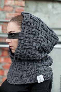 a woman wearing a gray knitted scarf with a hood on her head and black eye patch