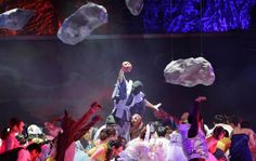 a group of people standing on top of each other in front of a stage with rock formations