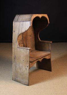 an old wooden chair sitting on top of a carpeted floor next to a black wall