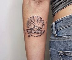 a woman's arm with a shell tattoo on the left side of her arm