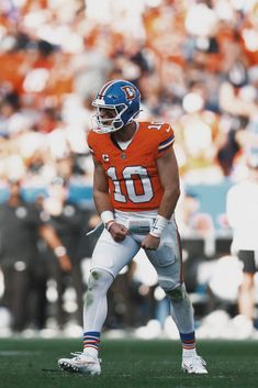 a football player standing on the field with his hands in his pockets and looking down