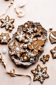 gingerbread cookies decorated with white snowflakes on a plate next to ribbon and ornaments