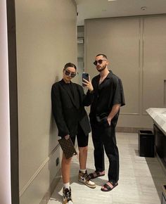 two people standing next to each other in a bathroom taking a selfie with their cell phone