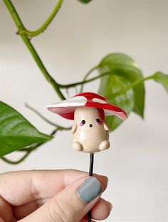 a tiny mushroom sitting on top of a toothpick in front of a plant