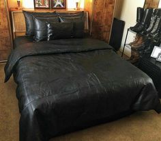 a black leather bed in a bedroom next to a chair and table with pictures on the wall