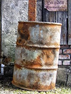 an old rusty barrel sitting in front of a building