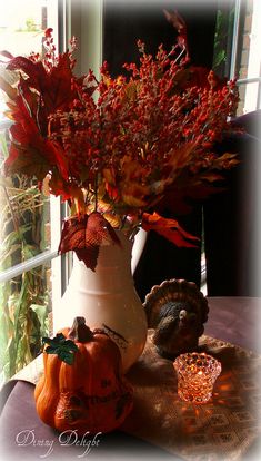 a vase filled with lots of red flowers next to a turkey and some pumpkins