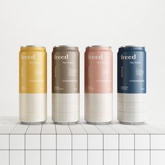 three cans of iced tea on a tiled countertop next to a white tile wall