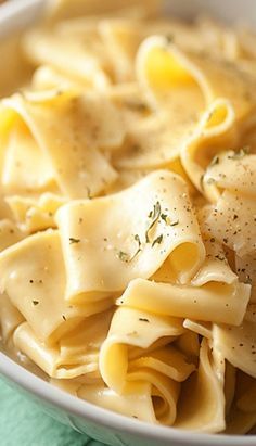 a white bowl filled with pasta covered in parmesan cheese and seasoning sprinkled on top