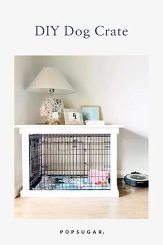 a dog cage sitting on top of a white table next to a lamp and pictures