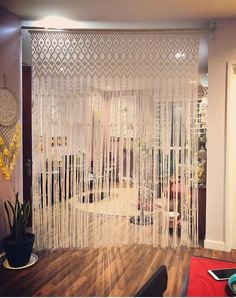 a living room with a white sheer curtain and wooden floors in front of the door