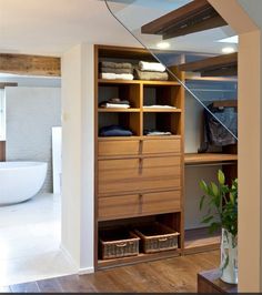 an open closet with drawers and shelves next to a bathtub in a bathroom area