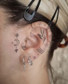 a woman with some piercings on her ear and behind her ear is a pair of scissors