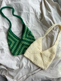 two crocheted bras laying on top of a white bed next to each other