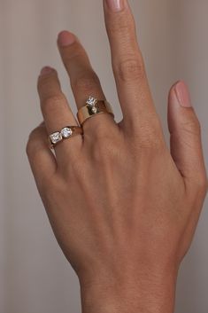 a woman's hand with two gold rings on top of her finger and one diamond in the middle