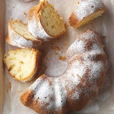 a cake that has been sliced and is sitting on a piece of parchment paper with powdered sugar