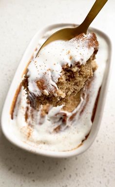 a spoon with some food in it on a white table and the bowl is filled with ice cream