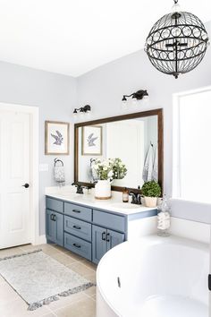 a bathroom with blue cabinets and a white bathtub next to a large mirror on the wall