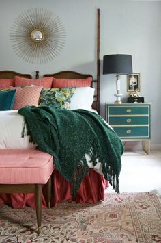 a bedroom with a bed, dresser and mirror in the corner that has a green blanket on top of it