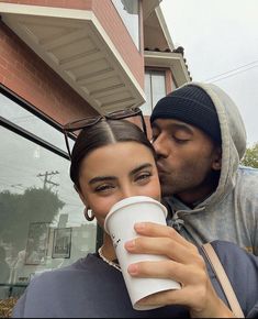 a man kissing a woman while holding a coffee cup