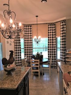 a kitchen with black and white checkered curtains, granite counter tops, and an island