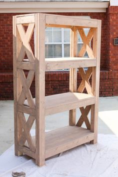 a wooden shelf sitting on top of a white cloth covered ground next to a brick building