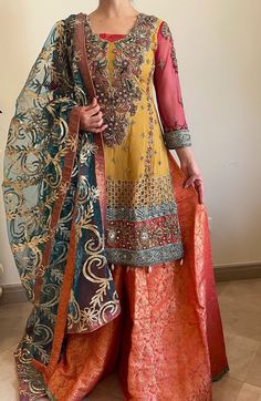 Representing ethnic clothing, handmade in Pakistan. This is the perfect bridal outfit! Comes with - Multi colored Shirt filled with handwork. - Jamawaar Sharara in tea pink. - Gota dupatta in green.  We do not accept returns/exchanges. Please allow slight color and design variations. Semi-stitched Palazzo Set With Dupatta For Wedding, Eid Sharara With Intricate Embroidery And Straight Kurta, Yellow Raw Silk Dress With Intricate Embroidery, Gold Embroidered Palazzo Set For Wedding, Wedding Gold Palazzo Set With Intricate Embroidery, Raw Silk Sharara With Dabka Work For Wedding, Dabka Work Sharara In Raw Silk For Wedding, Designer Sharara With Intricate Embroidery And Straight Kurta, Chanderi Wedding Dress With Dabka Work