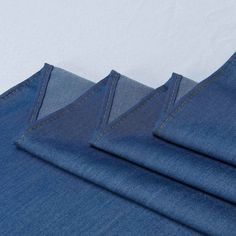 three pieces of blue denim folded on top of each other with stitching at the bottom