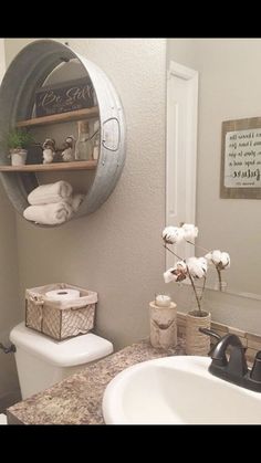 a white toilet sitting next to a bathroom sink under a metal shelf filled with towels