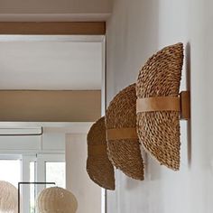 several woven hats hang on the wall in a room with white walls and flooring