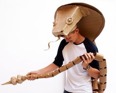 a man wearing a paper mache hat and holding a large wooden object in his hands