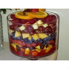 a fruit salad in a glass bowl with oranges, raspberries and blueberries