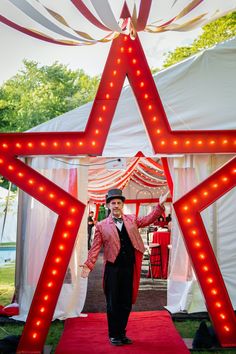 a man standing in the middle of a red carpeted area with lights on it