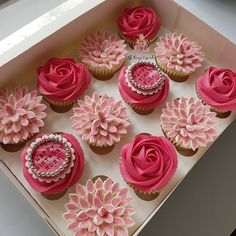 cupcakes decorated with pink frosting and flowers in a box on a table