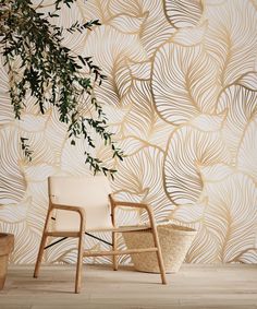 a white chair sitting in front of a wall with leaves on it and a basket next to it