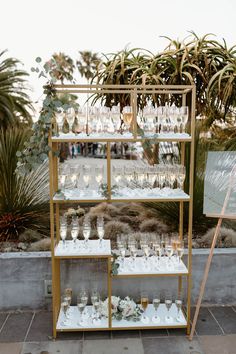 a display case filled with lots of glasses on top of a tiled floor next to palm trees