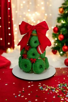 a small christmas tree made out of green doughnuts with a red bow on top