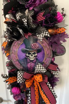 a halloween wreath with a skeleton wearing a hat and purple, black and orange decorations