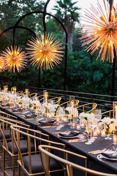 a long table is set with black linens and gold chairs for an outdoor event