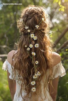 the back of a woman's head with flowers in her hair and long curly hair