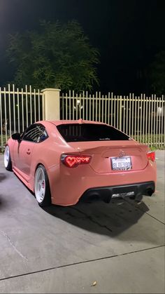 two pink sports cars parked next to each other