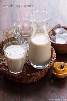 there are three glasses on the table with milk and orange slices in front of them