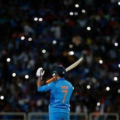 a man holding a bat on top of a field in front of a stadium filled with people