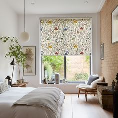 a bedroom with a bed, chair and window covered in roman blind shades on the windowsill