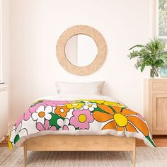 a bed in a room with a flowered comforter on it and a round mirror above the bed