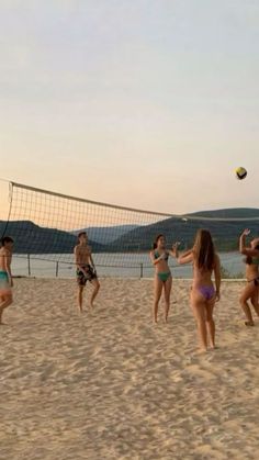 people playing volleyball on the beach at sunset