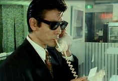 a man in suit and sunglasses talking on a phone