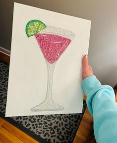 a person holding up a drawing of a drink with a lime slice on the rim